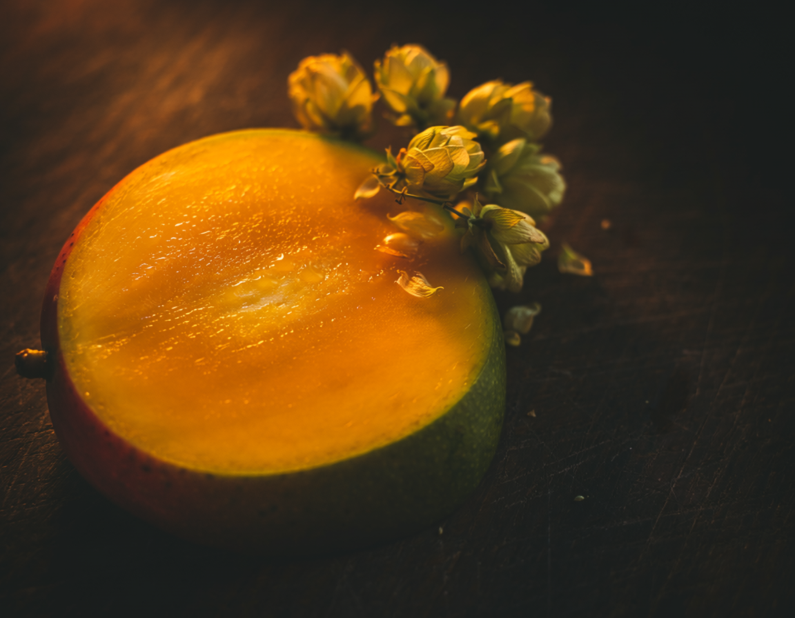 Close-up of a ripe mango and dried hops on a warm wood surface — Ritual Cannabis terpene series